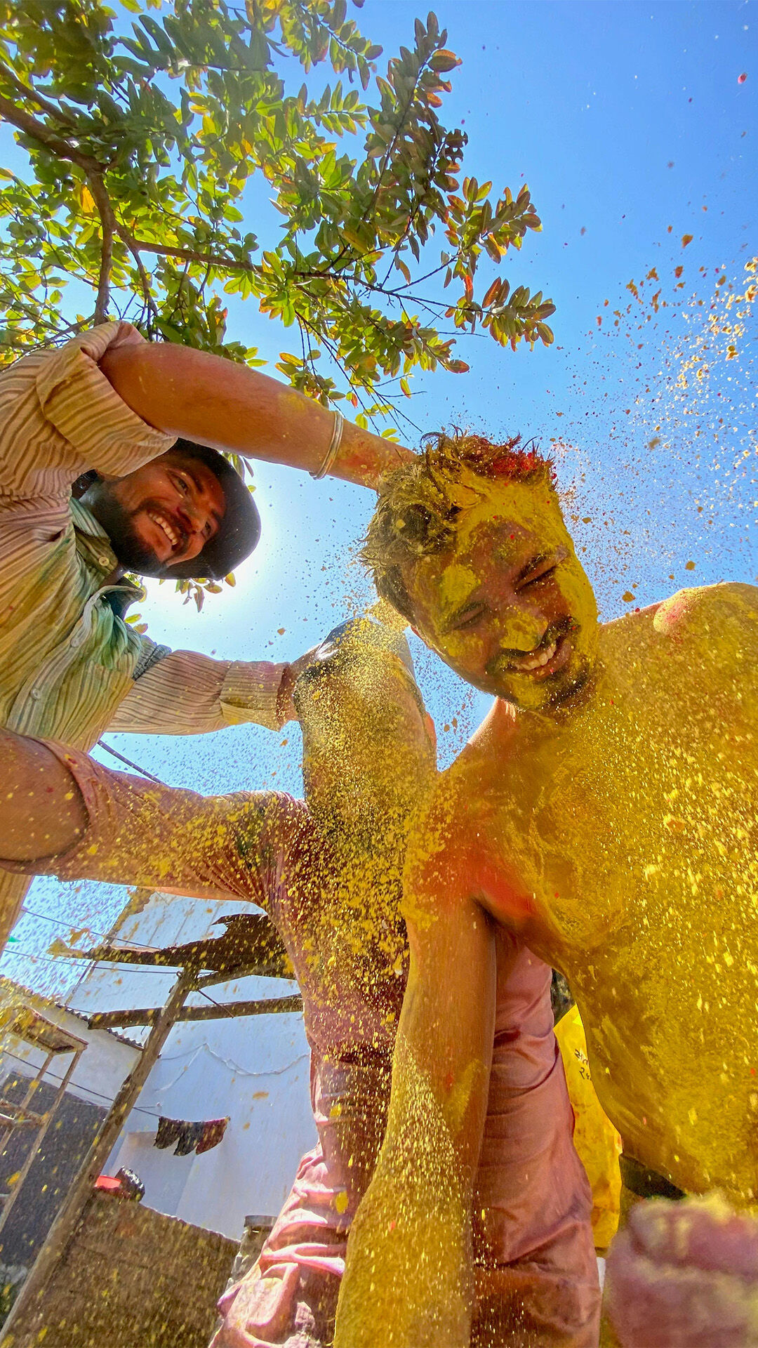 A man putting yellow colour on his freinds 